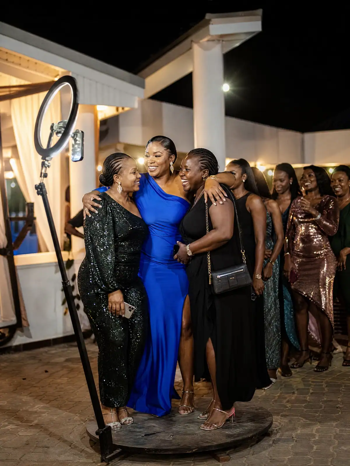 Host celebrating with friends beside a brightly lit 360 photo booth in Freetown
